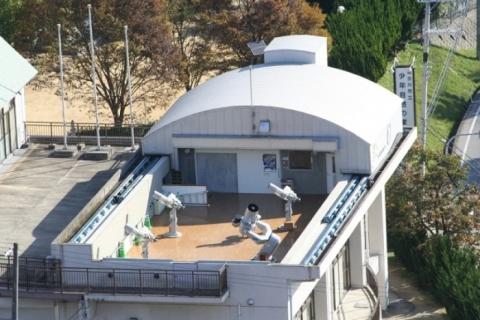 建物の屋上に設置された、4台の白い望遠鏡を上空から映した写真