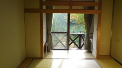 畳敷きで窓にカーテンがついている宿泊館の和室の写真