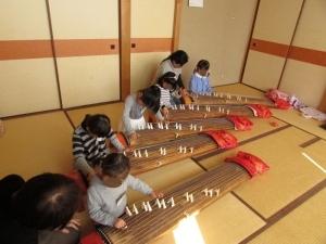 先生に教えてもらいながら琴の練習をする幼児の写真