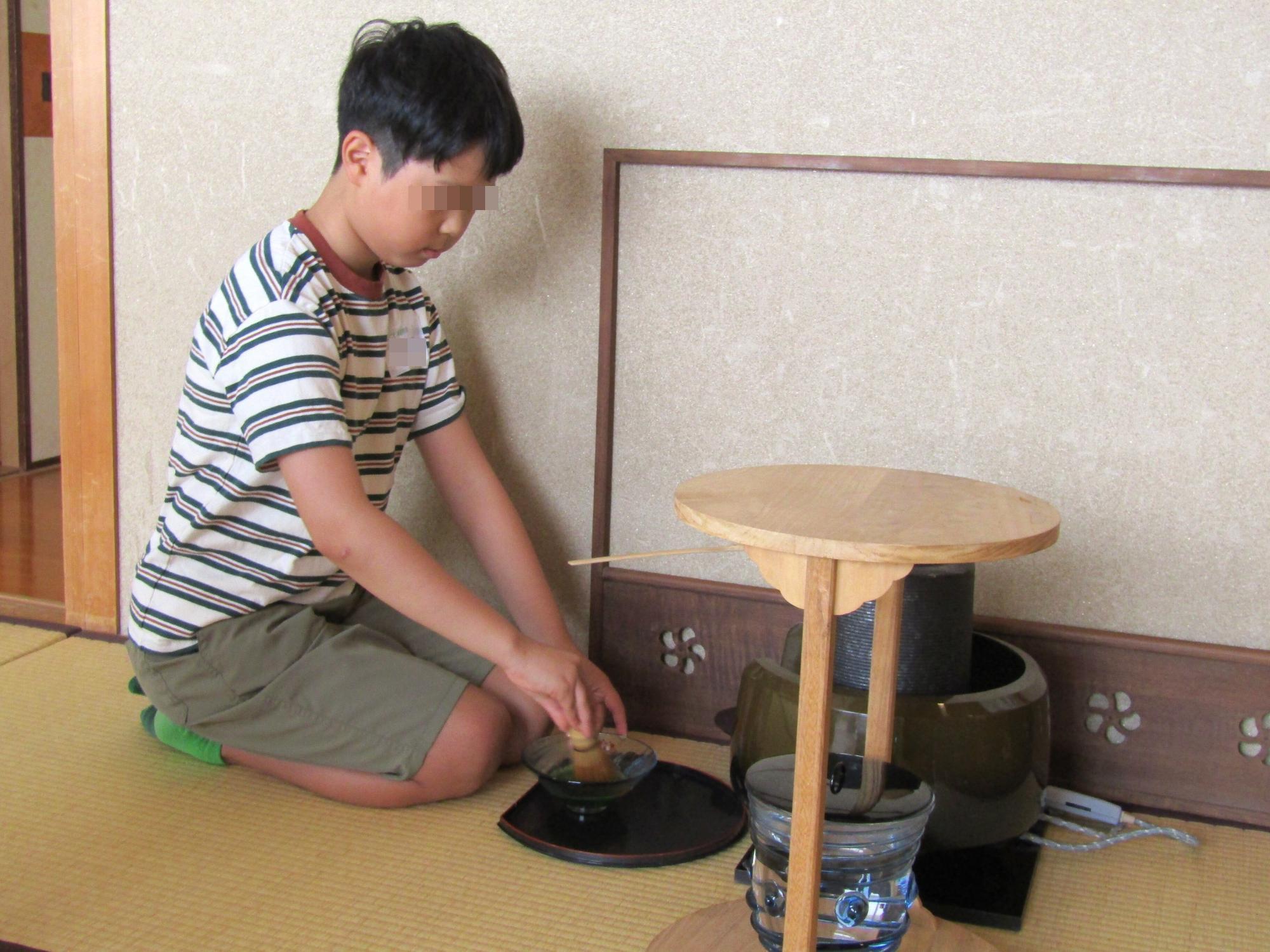先生に教わりながら、一人でお茶をたてる男の子