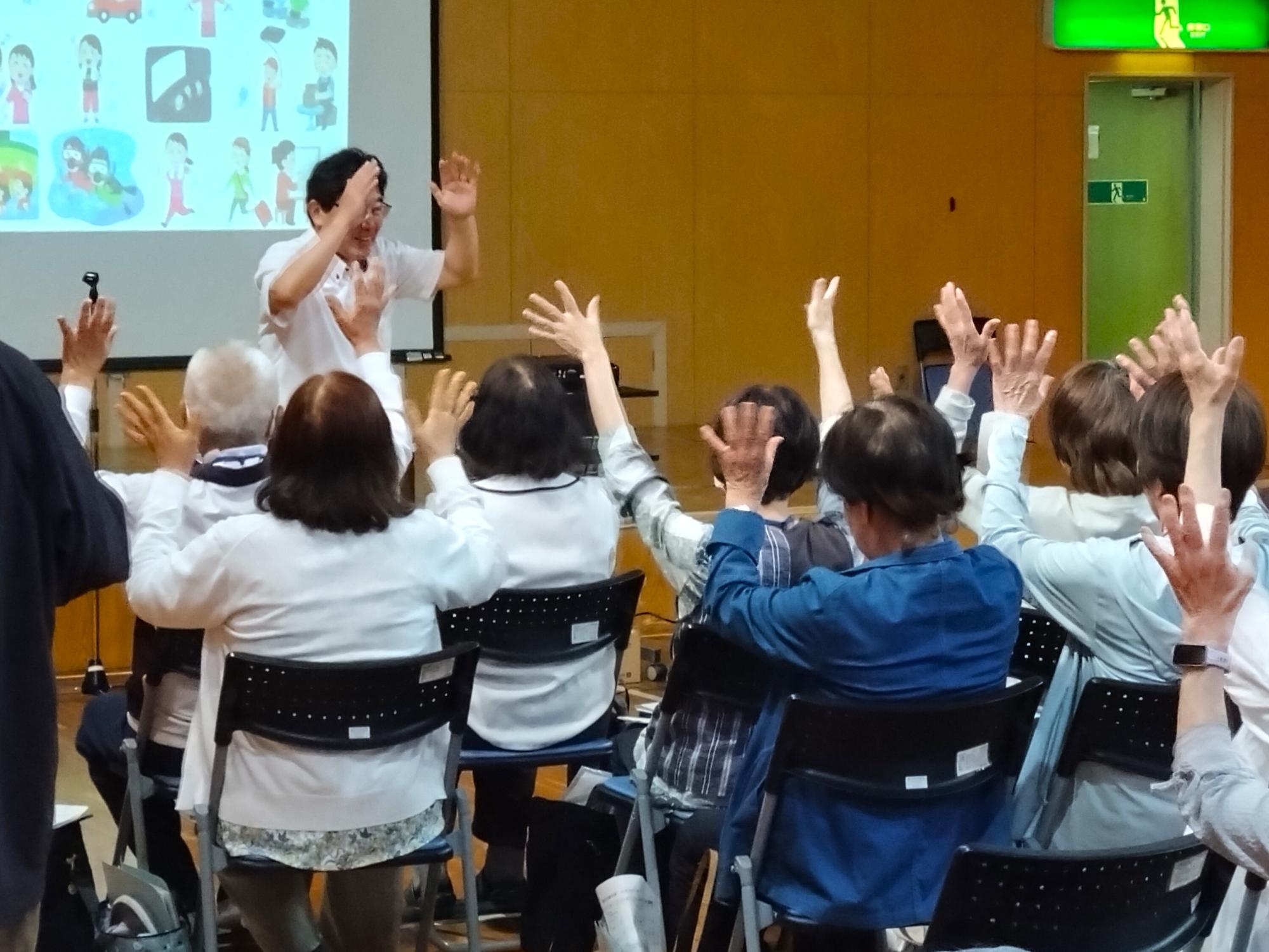 拍手の手話を、講師に教えてもらっている学生たち