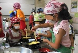 わいわいクラブで卵焼きの調理に挑戦している女子小学生の写真