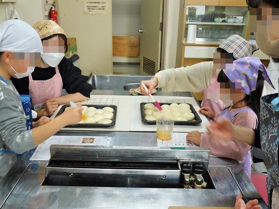 親子でパン生地に卵を塗る様子
