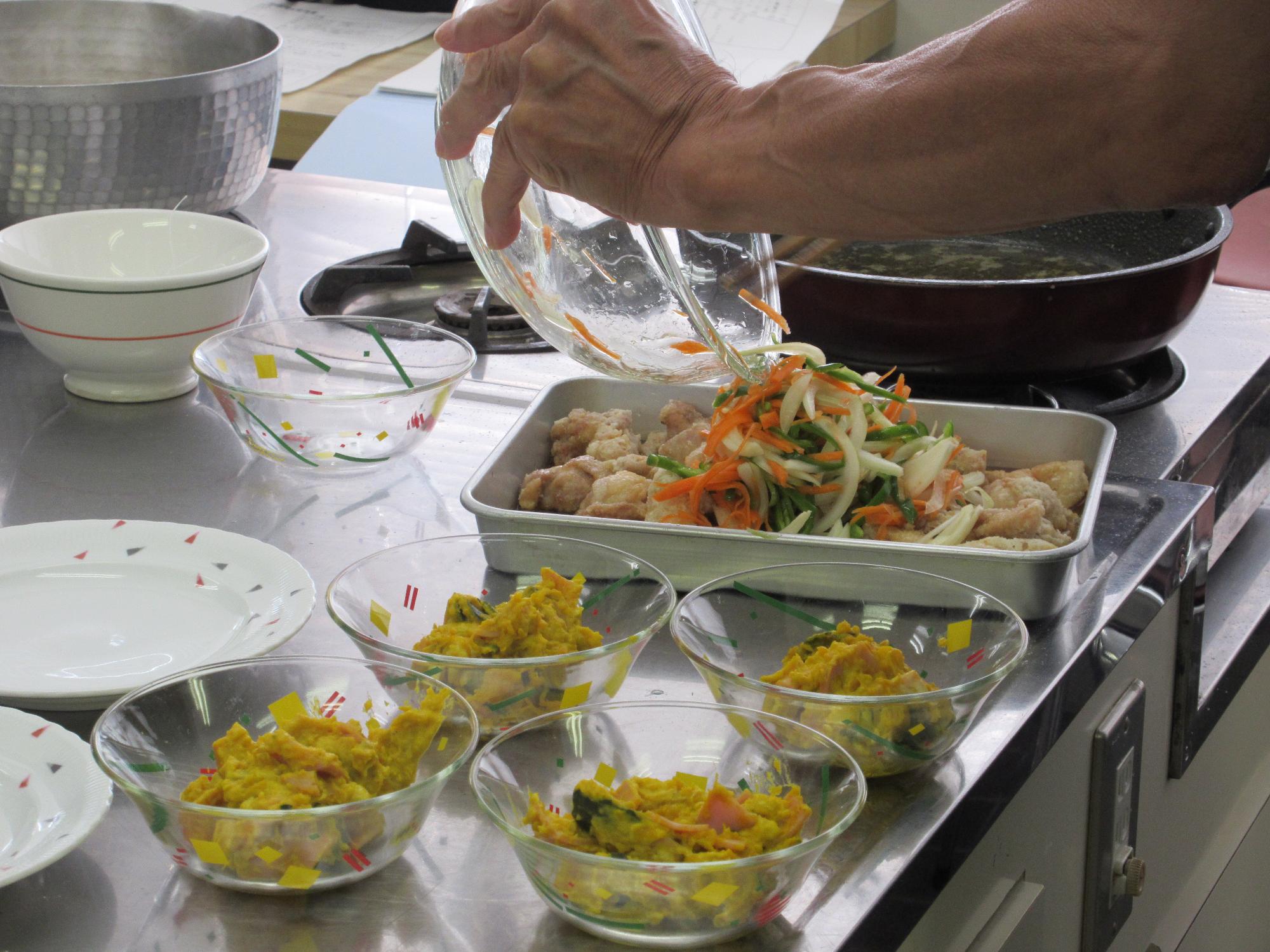 男性料理教室で、楽しく手分けしてお料理を盛り付けしている様子です。