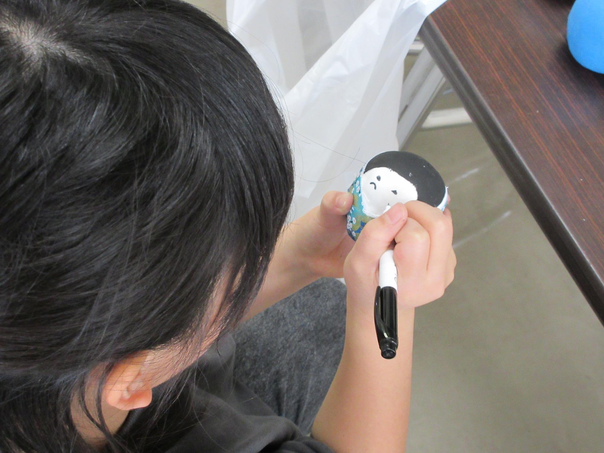 ひな飾りに顔を描く様子