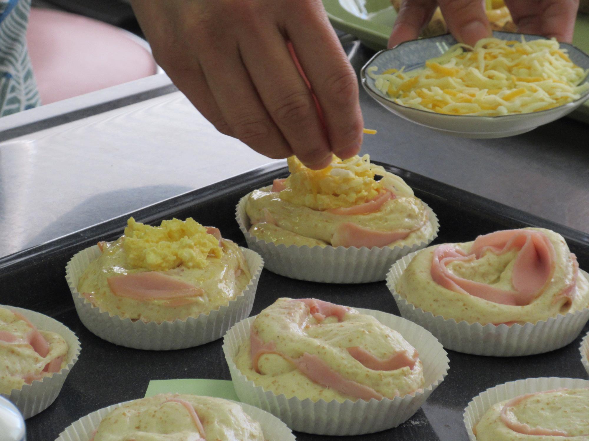 ハムのパンにチーズをかける作業の様子