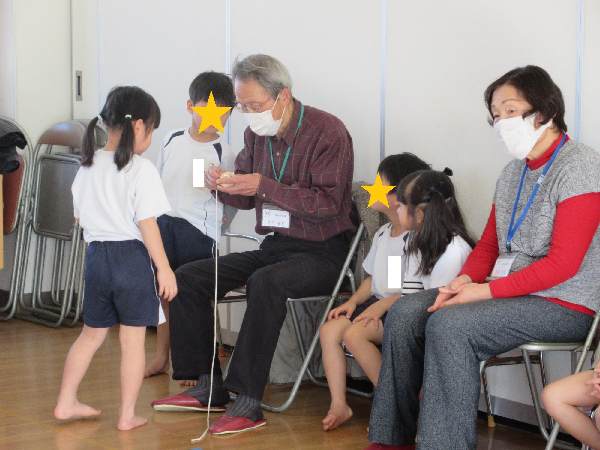 コマを上手く回す紐の結び方を教えているようす