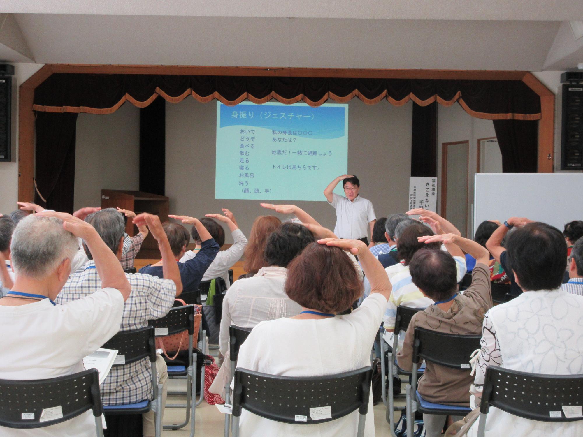 頭の上に手のひらを置くポーズで身長を示す手話を学ぶ