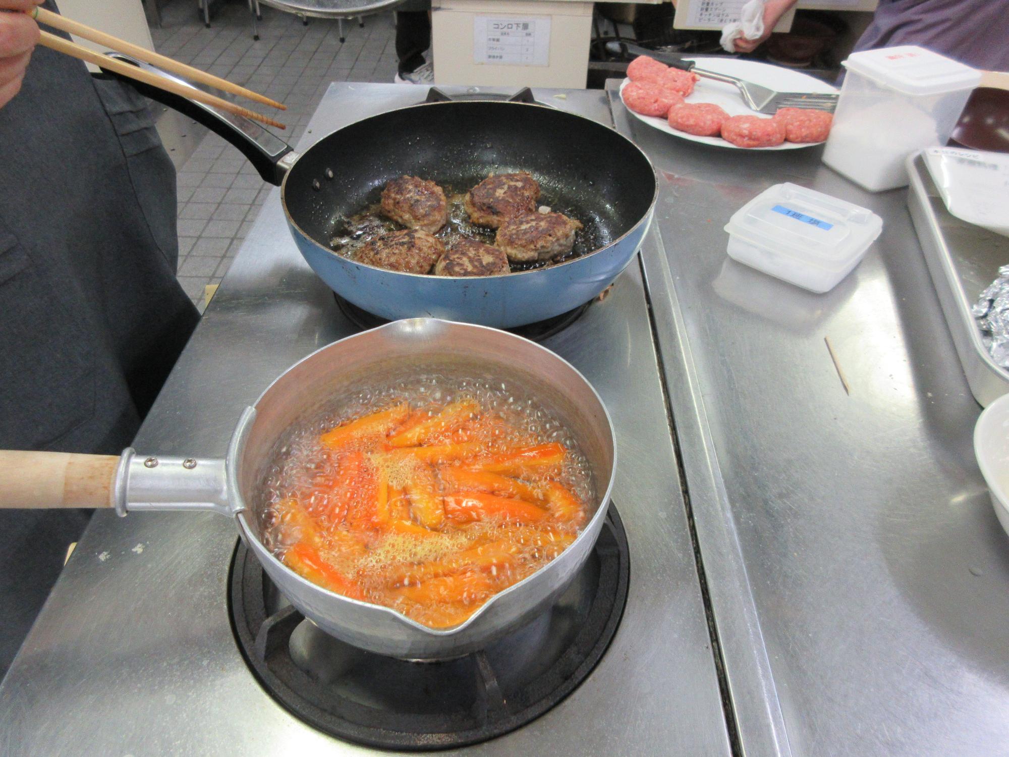 ハンバーグステーキとニンジンのグラッセを火にかけるようす