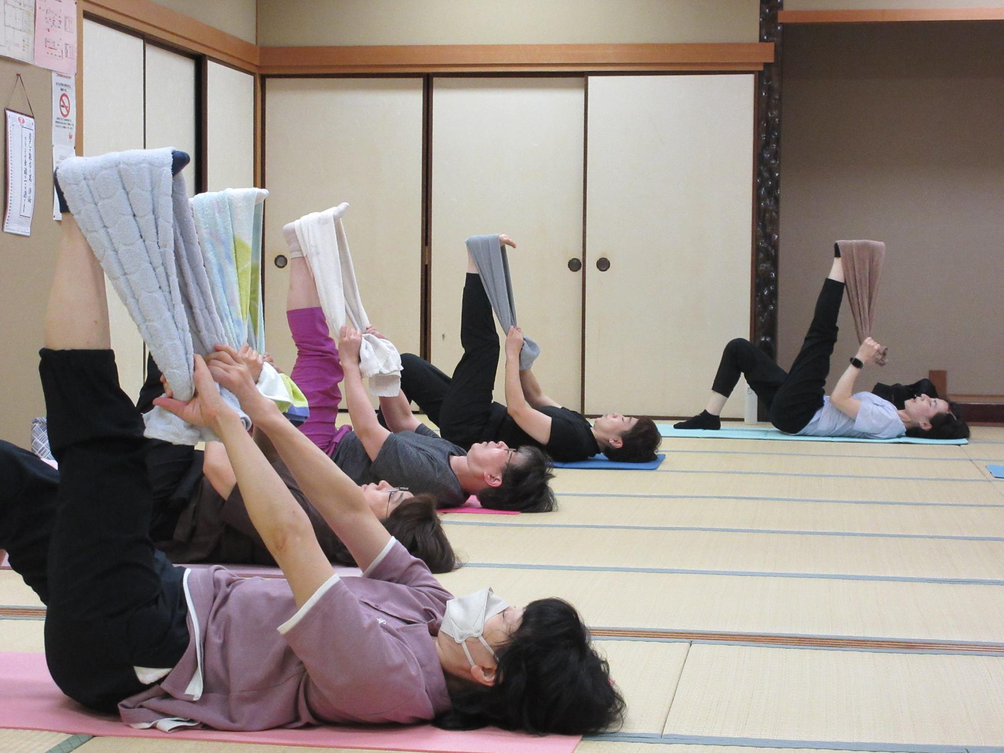 仰向けに寝転び、タオルに足をかけ、天井に向かって膝を伸ばす動き