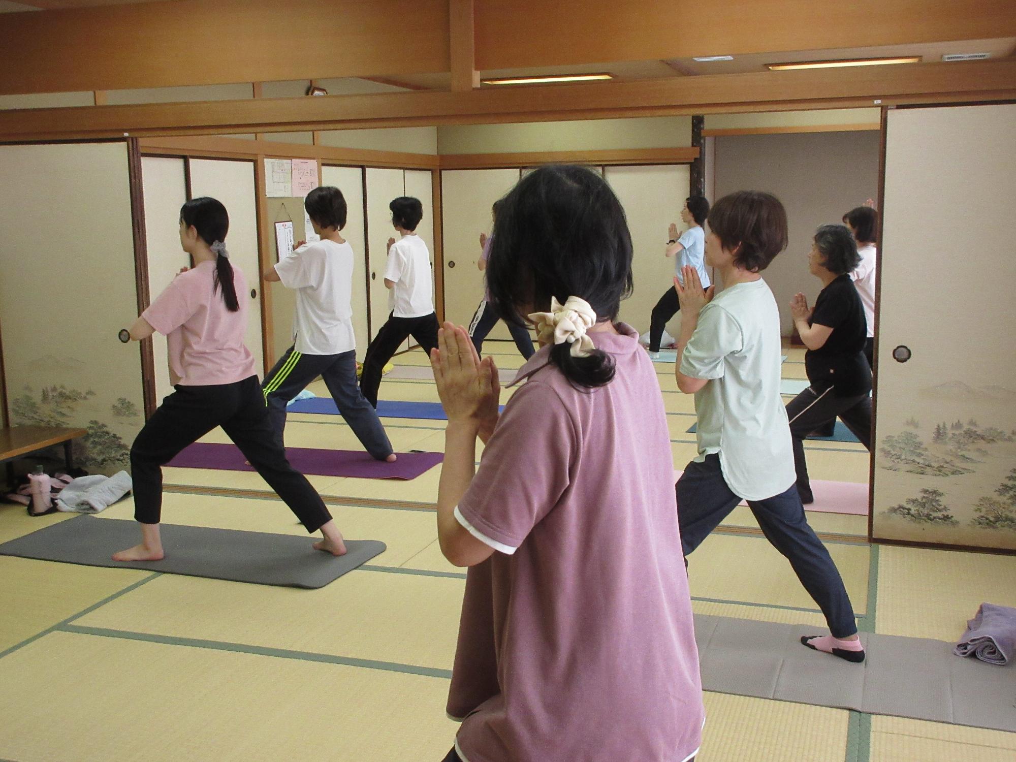 胸の前で手を合わせ、足を縦に開きポーズをとる様子