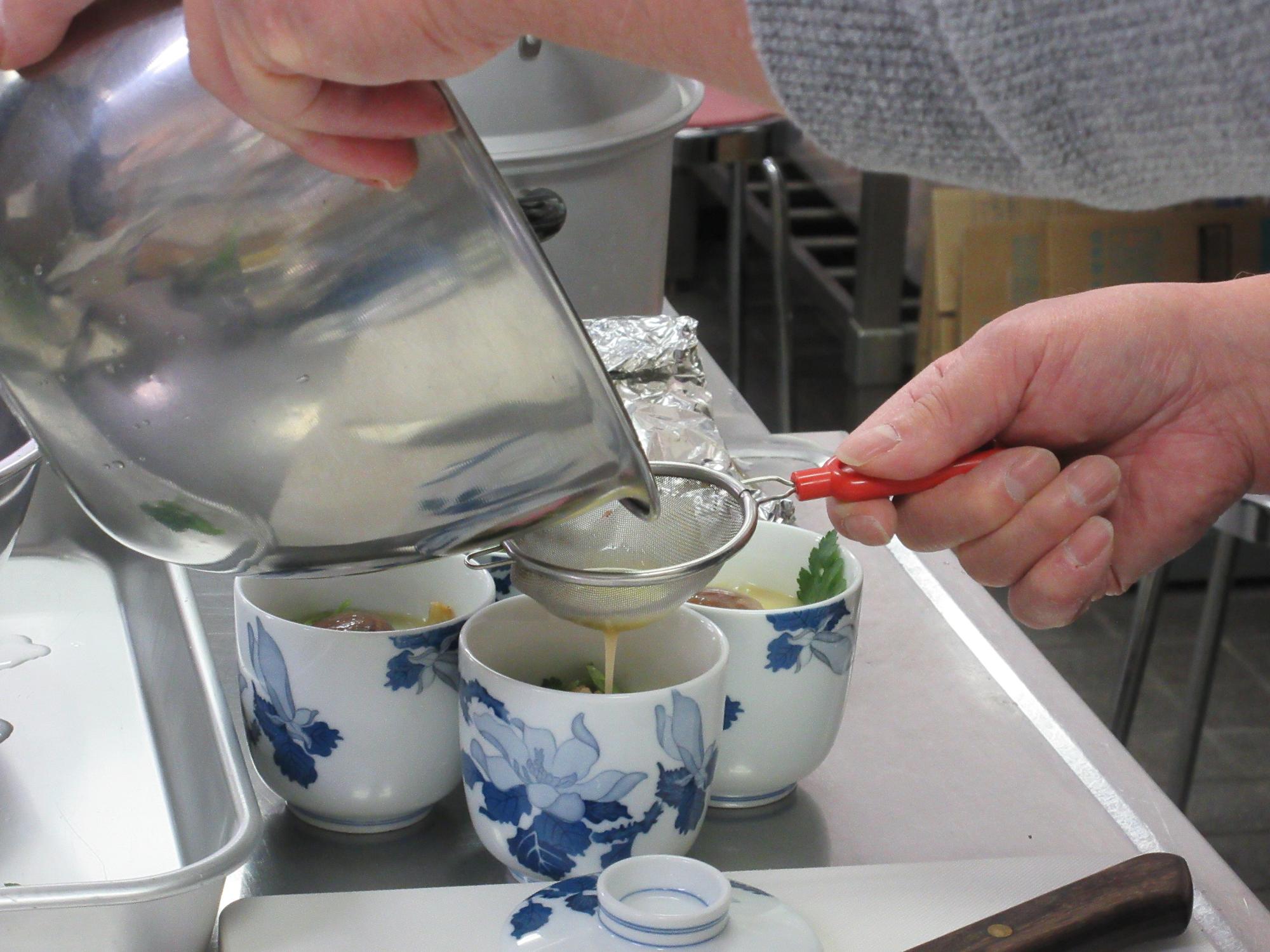 茶こしで卵液をこし、茶わん蒸しを作る様子