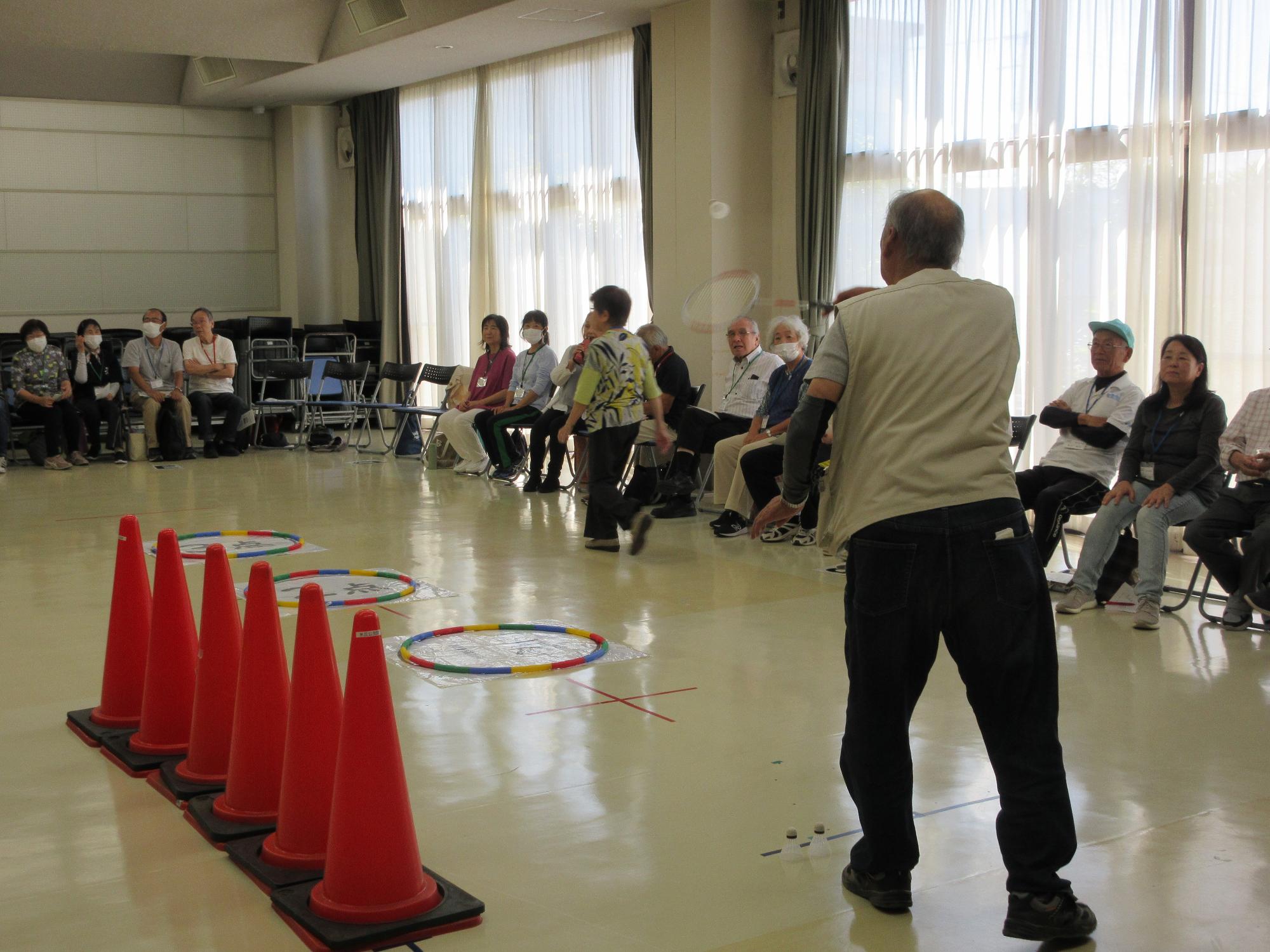 バドミントンの羽を打って、サークル内の得点を狙うようす