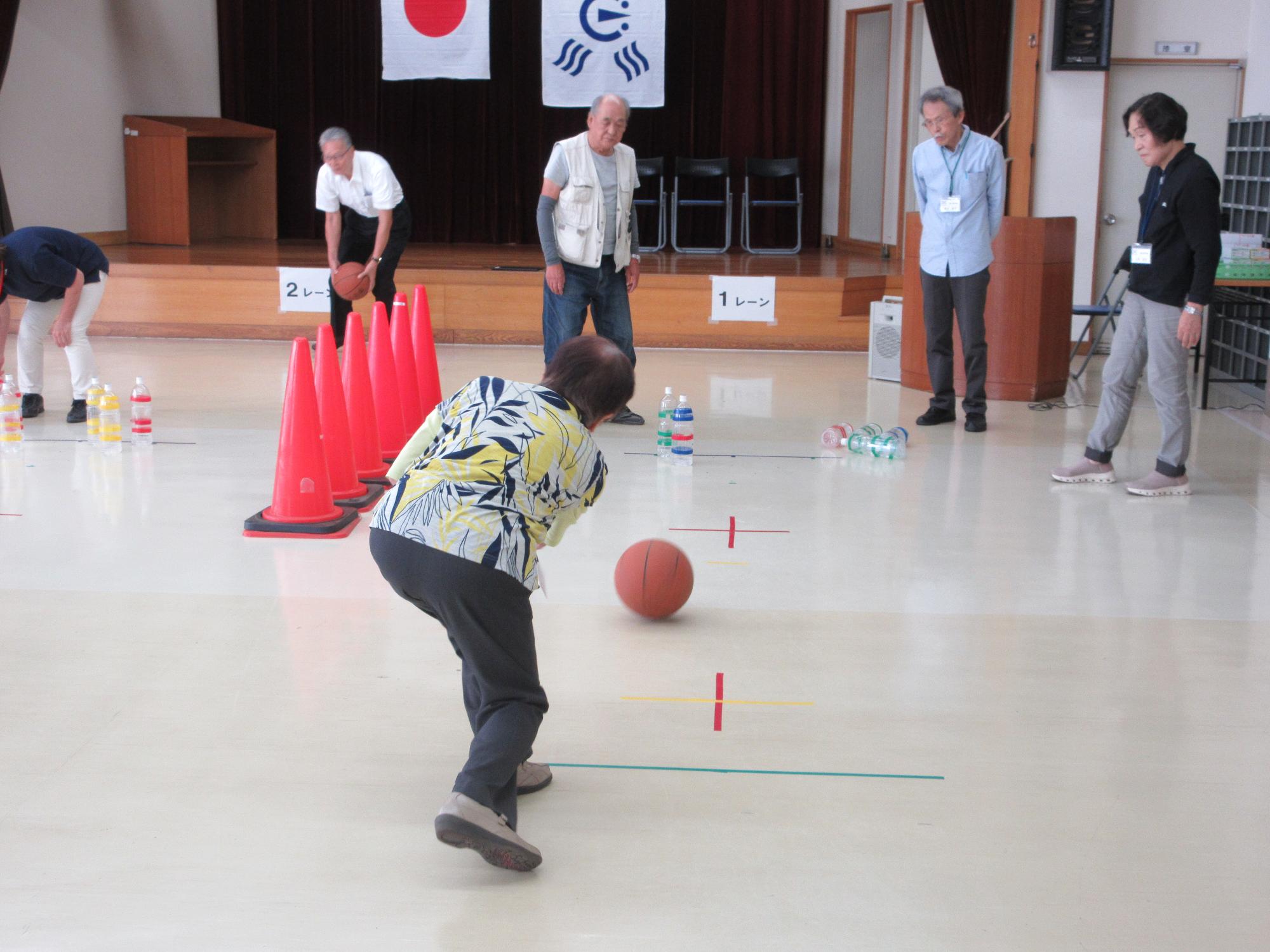 ボールを転がしてペットボトルを倒し、スペアを狙うようす