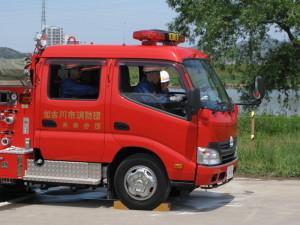 車輪が固定された車両で放水訓練を行うために消防車に乗り込んでいる消防団員たちの写真