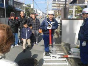 消防団員が地域住民へ消火栓の使用法を指導している写真