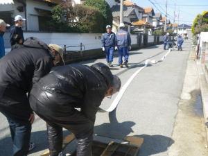 道路に長いホースが伸び、ホースと消火栓を接続している写真