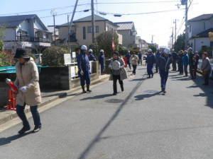 消火訓練で住民がホースを持ち道路を走っている写真