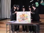5名の女性が幼稚園で紙芝居を用いた訓練指導を行っている写真