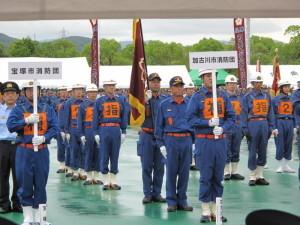 ポンプ操法大会の開会式で整列する加古川市消防団員と他の地域の消防団員の写真