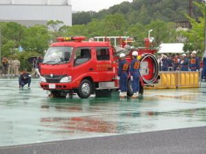 ポンプ操法大会で消防車のそばで待機する二人の消防団員