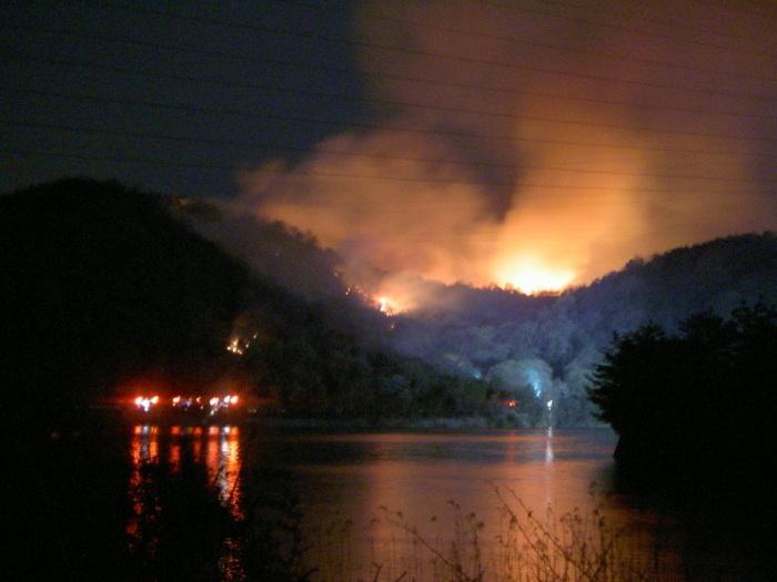暗闇の中、林野火災により山々が炎や煙を上げている写真